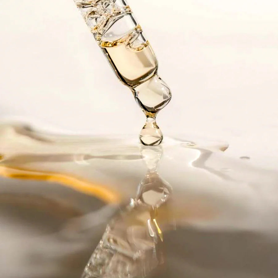 Close-up of a dropper with liquid on a reflective surface