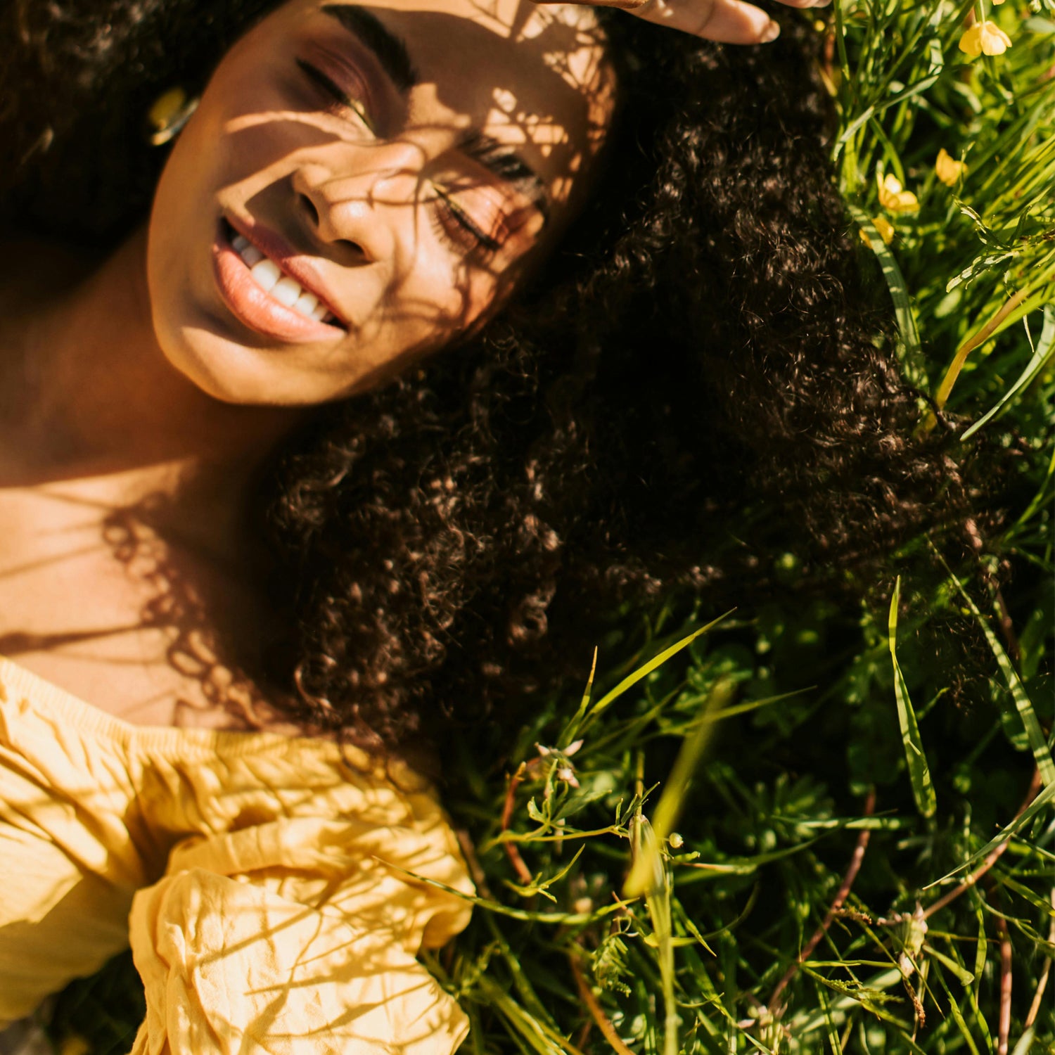 Person lying on grass with sunlight casting shadows