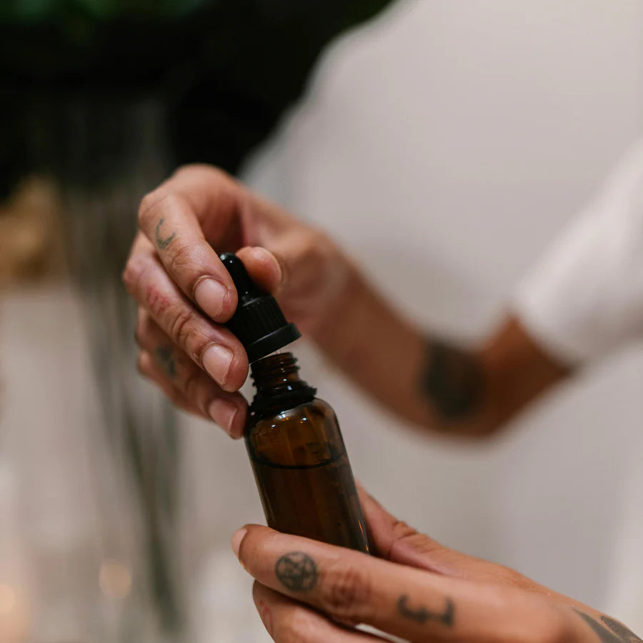 Person holding a brown glass bottle with a dropper, blurred background